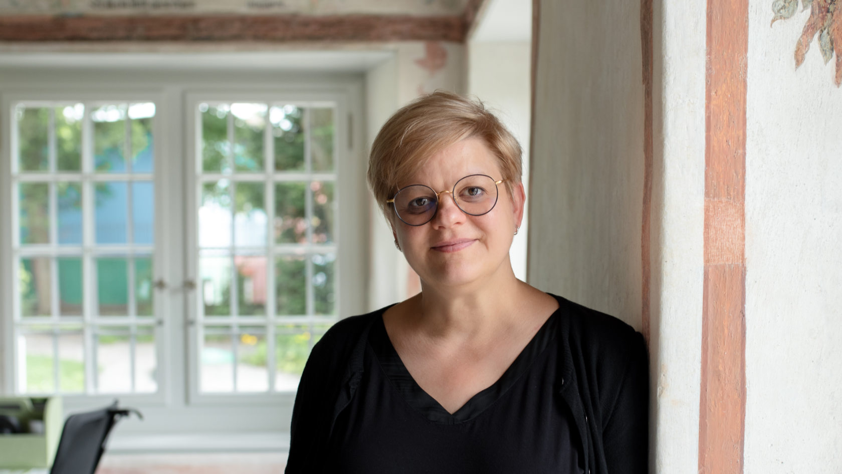 Ulla Blume in ihrem Büro, im Hintergrund ein Fenster.