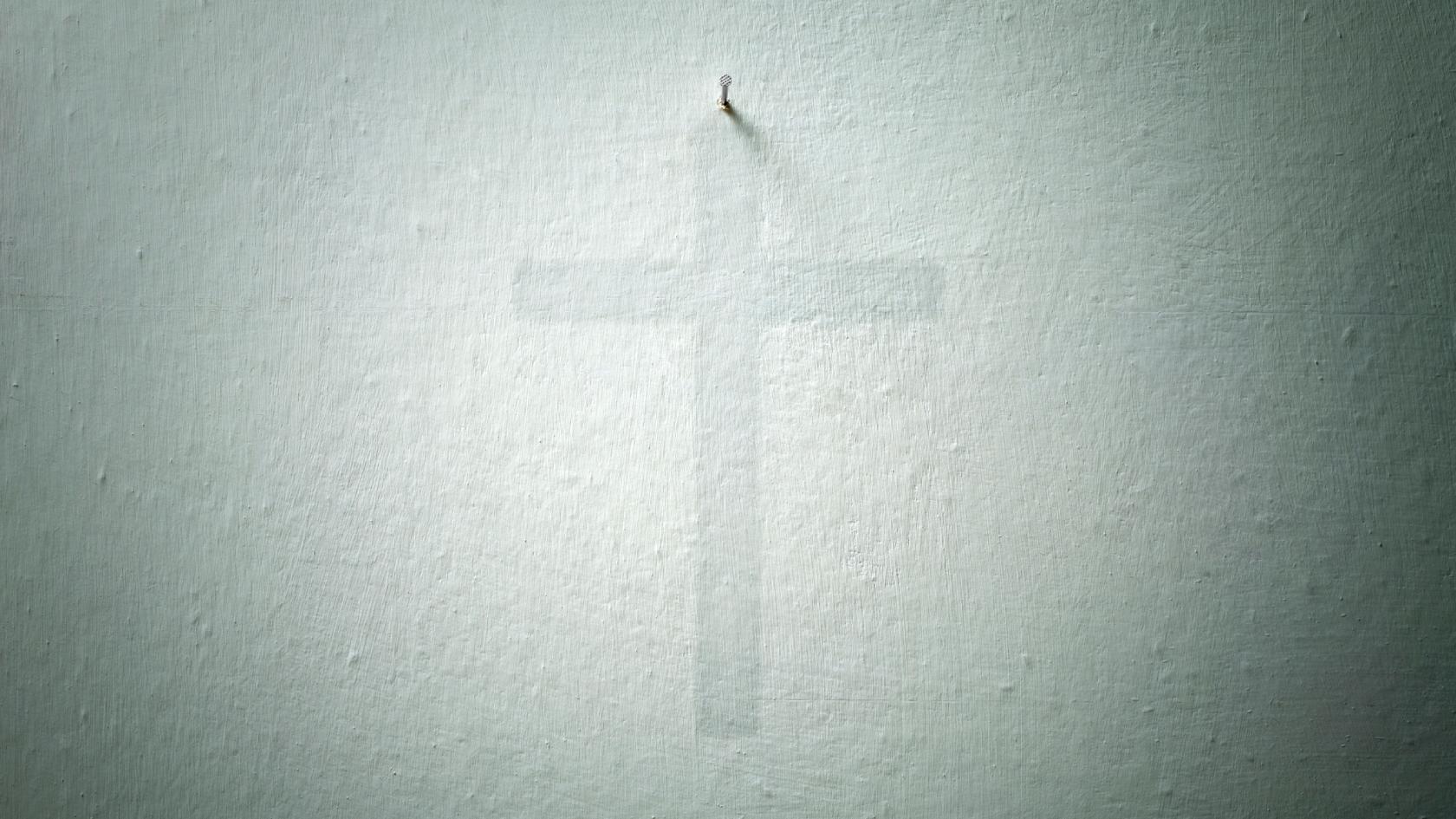 Schatten eines Kreuzes an der Wand