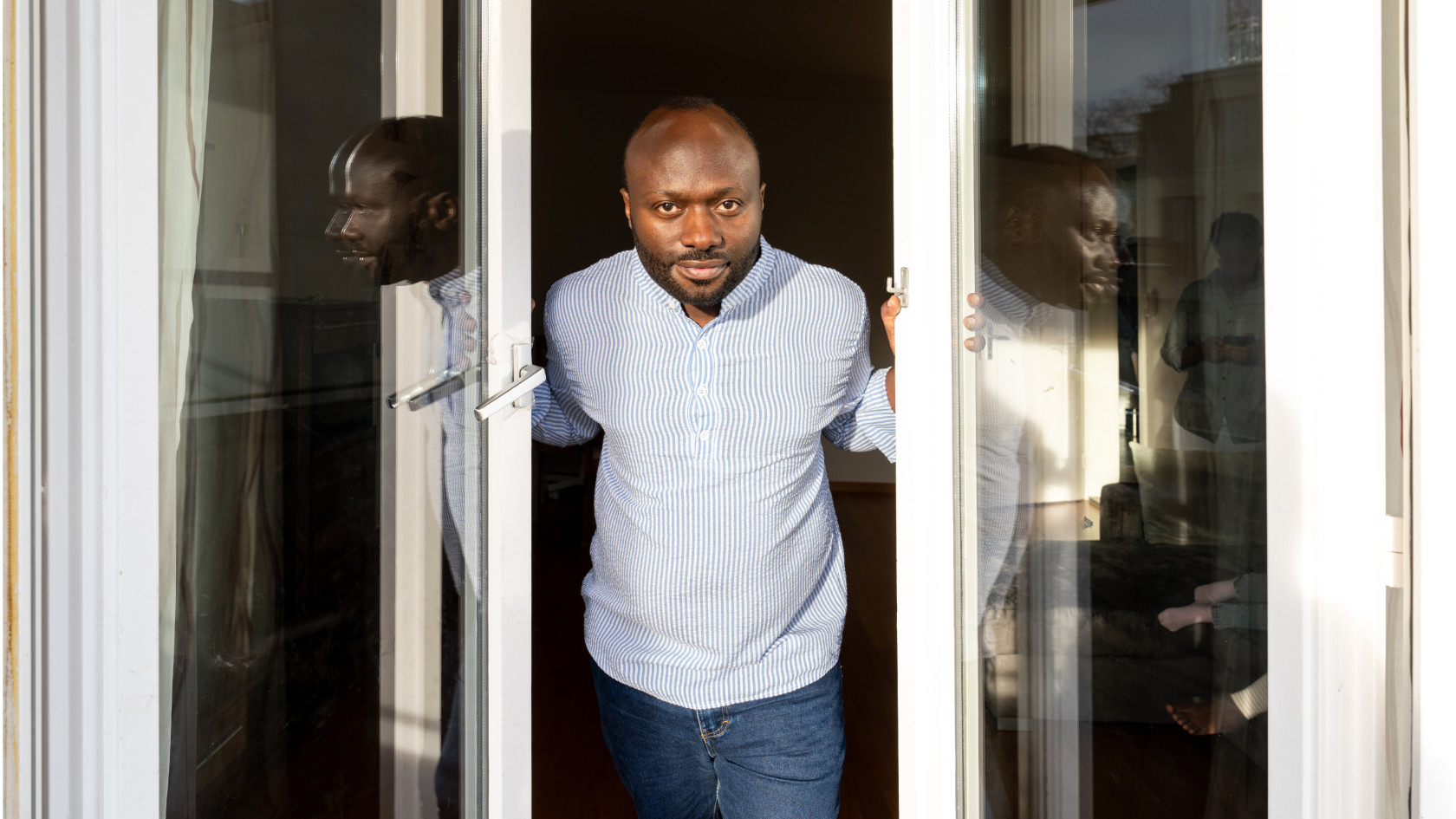 Celestin Mutuyimana lehnt sich aus einer offenen Glastür