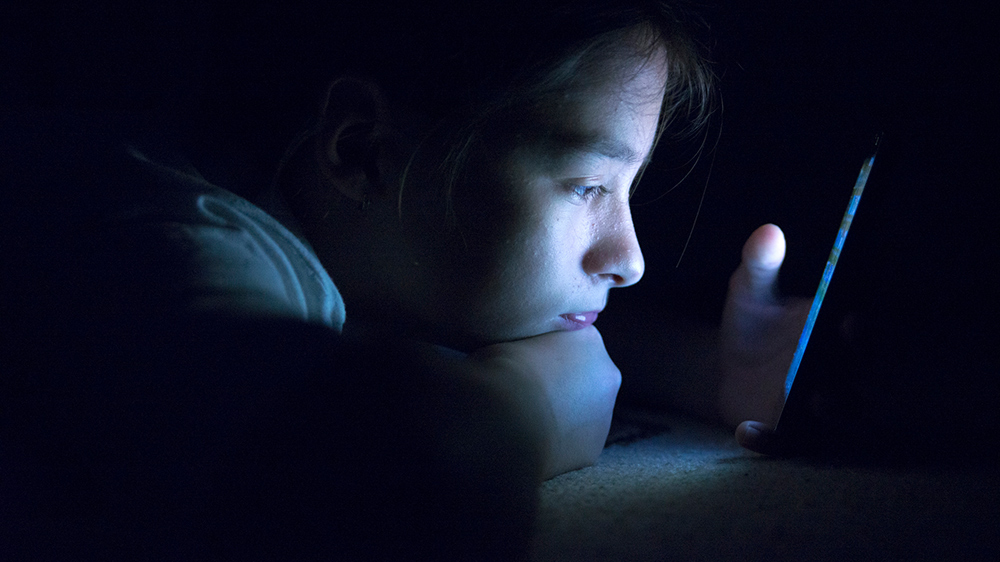 Kind nutzt Handy in der Nacht.
