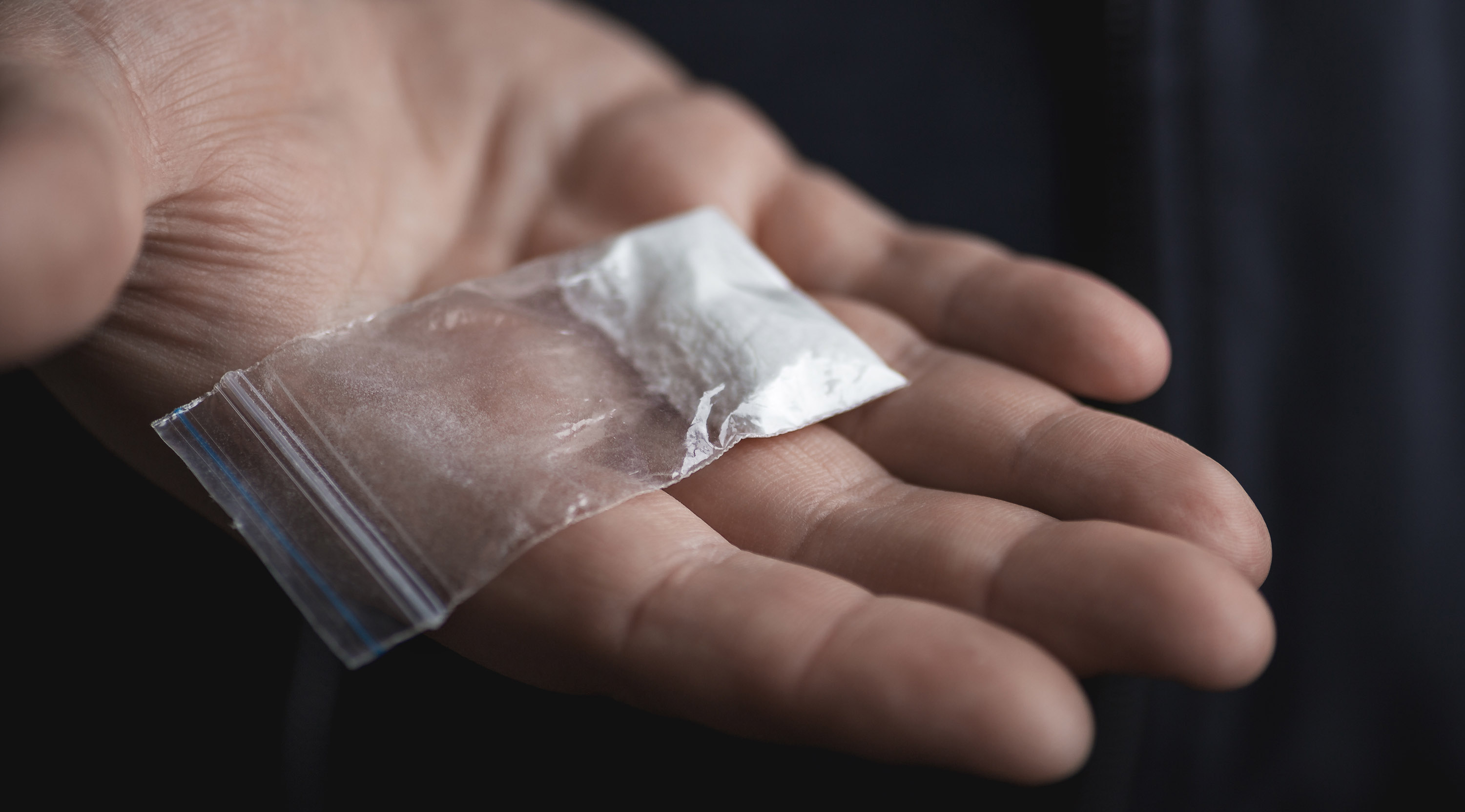 Beutel mit Kokainpulver auf Handfläche