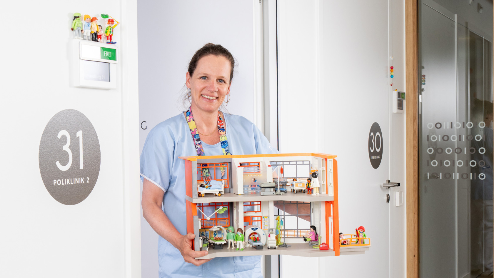 Psychologin Anna graf vor ihrem Büro im Universitäs-Kinderspital. Sie hält eine Playmobil-Krankenstation in der Hand.