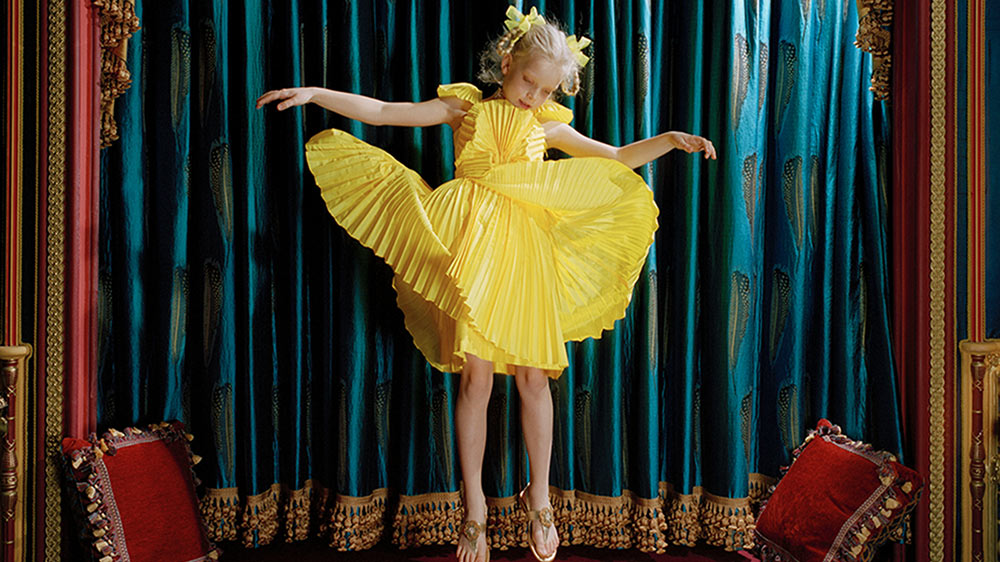 Ein Mädchen trägt ein Dior-Kleidchen und hüpft vor dem edlen kleinen Heimkino in ihrem Kinderzimmer.