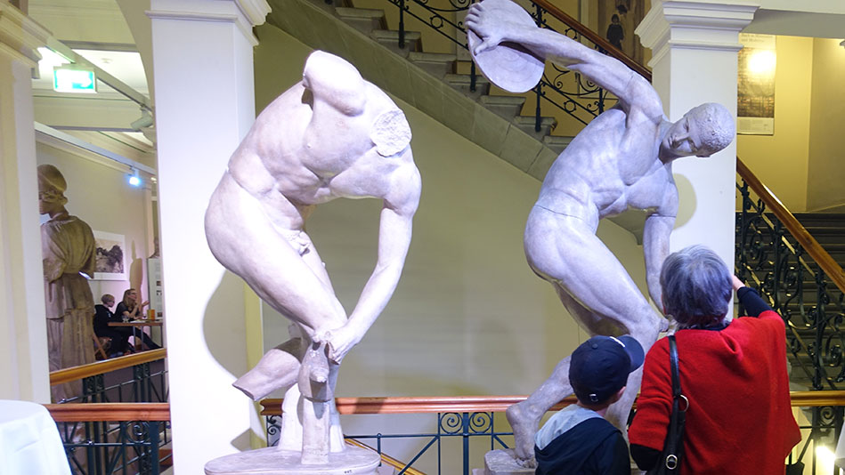 Grossmutter und Enkel bewundern den Diskobolos des Bildhauers Myron. Diese Darstellung eines Diskuswerfers gehört zu den bekanntesten griechischen Statuen überhaupt.
