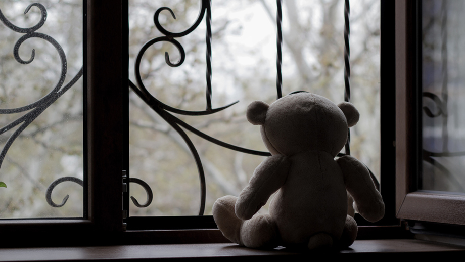 Symbolbild: Einsamer Teddybär hinter Fensterscheibe