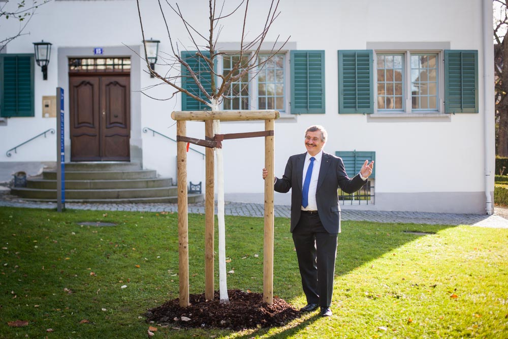 UZH-Rektor Michael Hengartner vor dem frisch gepflanzten Alumni-Bäumchen, einer Mirabelle de Nancy.