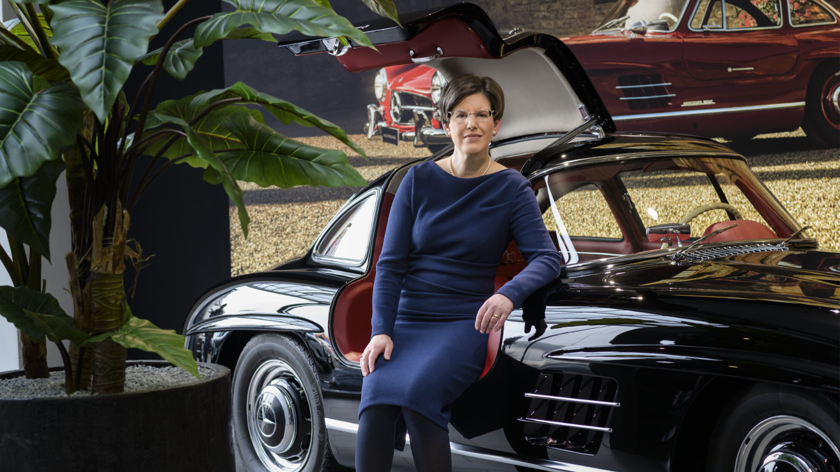 Karin Stüber sitzt in der geöffneten Tür eines alten Mercedes-Coupés