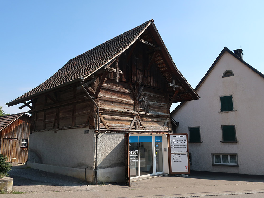 A heavily agricultural region, Dielsdorf is rich in historical solid wood and half-timbered storehouses. This storehouse in Dielsdorf is the only one remaining with a post-and-plank construction. It would have first been constructed entirely from wood. The storehouse – which originally had parking space for carts on the ground floor and a grain store on the first floor – dates back to 1646 and belongs to the farmhouse in the right of the photo but is a separate building, which was usual for the time. The dried grain could be stored there and was better protected from fire. (image used with permission)