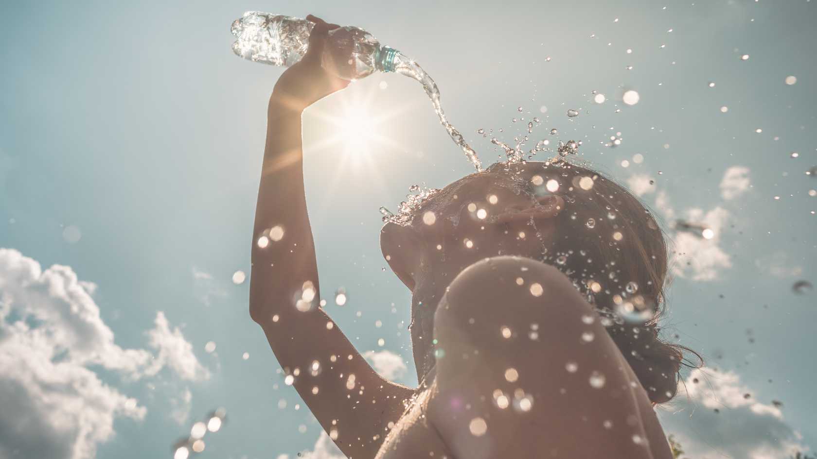 Eine Frau kühlt sich an einem heissen Sommertag mit Wasser ab.