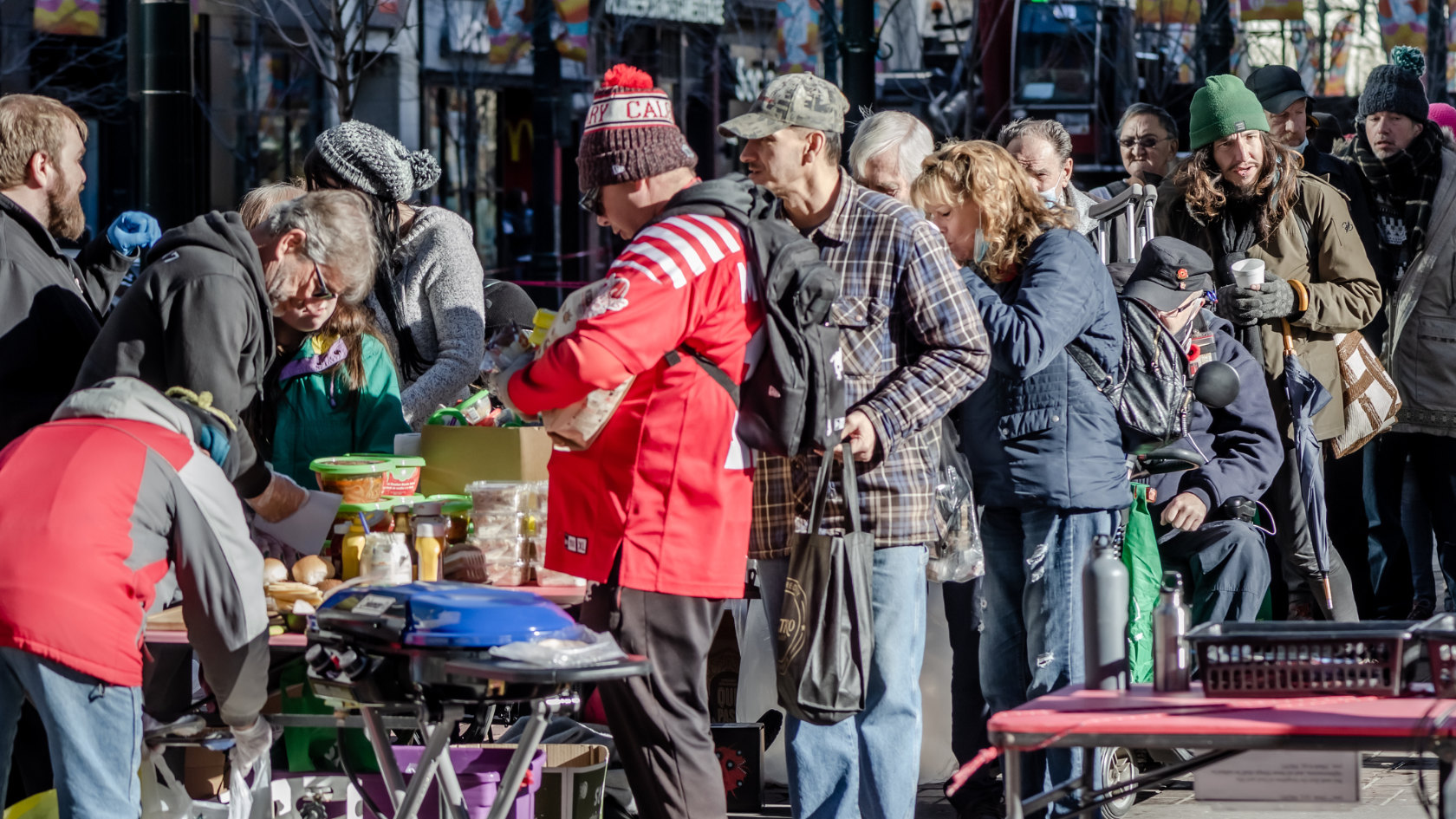 Zahlreiche Menschen stehen auf der Strasse in einer Schlange, um eine Gratis-Mahlzeit zu bekommen.