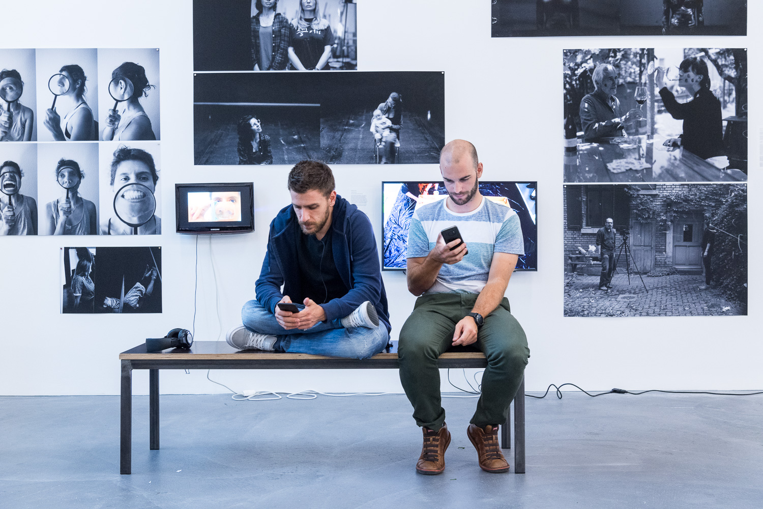 Focusing before the show: Doctoral candidate Davide Falanga and engineer Julien Kohler photographed shortly before taking the stage with their drones. The photos in the background were created in a seminar held by Polish artist Artur Zmijewski together with UZH doctoral candidates as part of the science festival. (Image: Frank Brüderli)