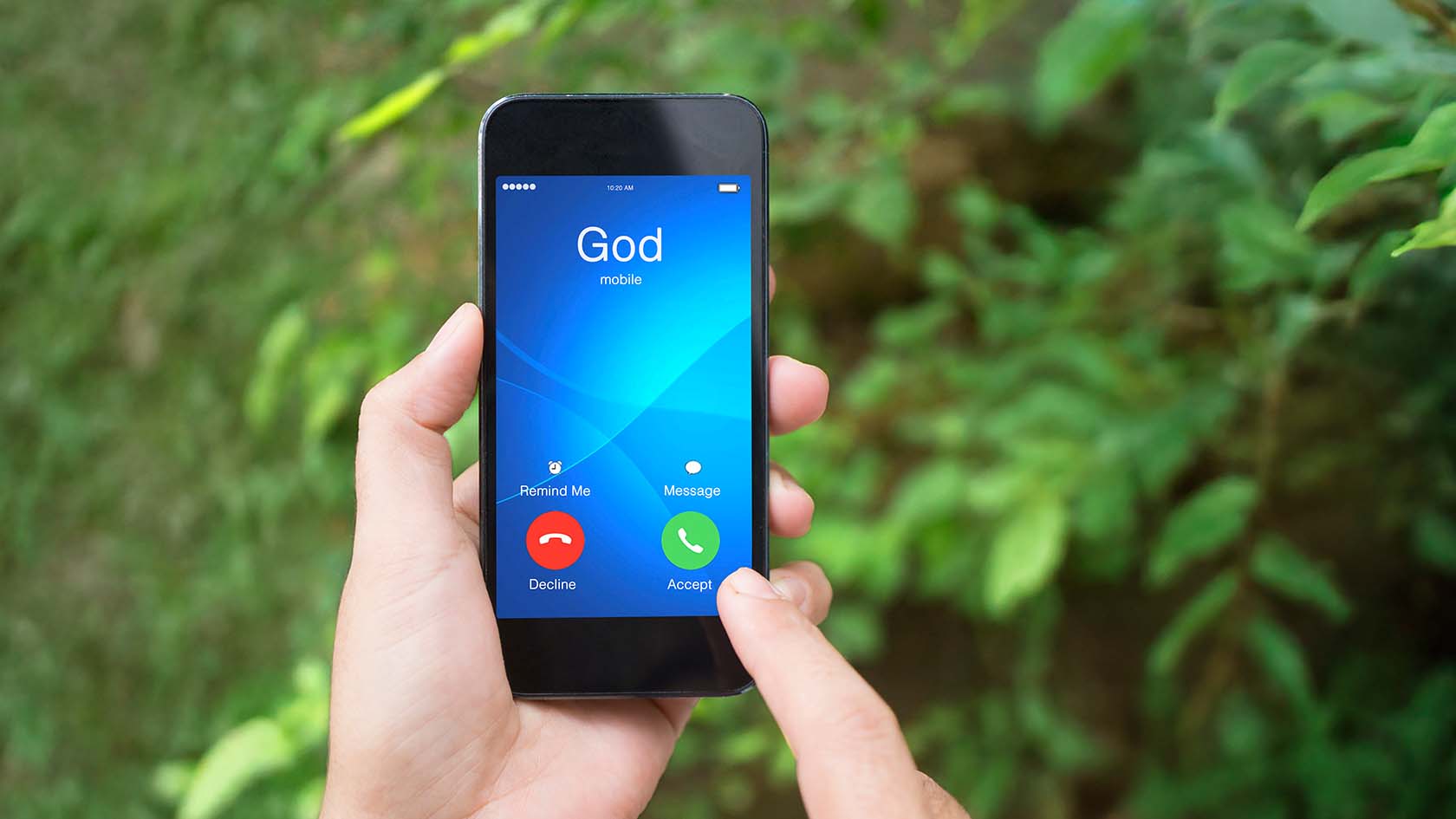Eine Hand hält ein Smartphone, auf welchem gerade ein Anruf von Gott hereinkommt.